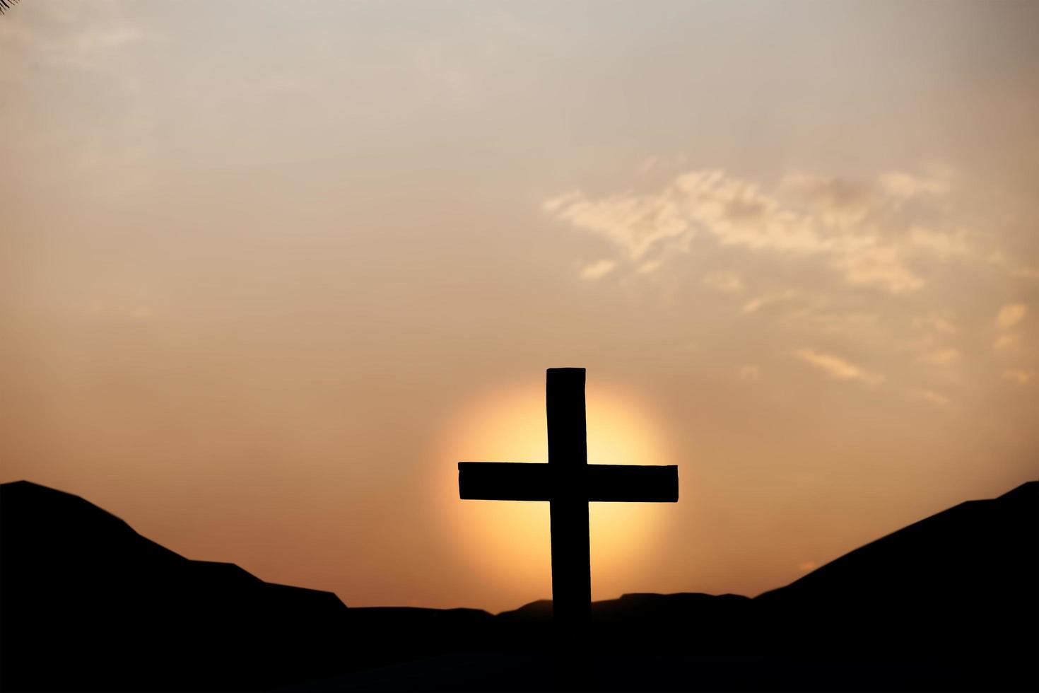 silhueta de cruz na montanha ao pôr do sol. conceito de religião. foto