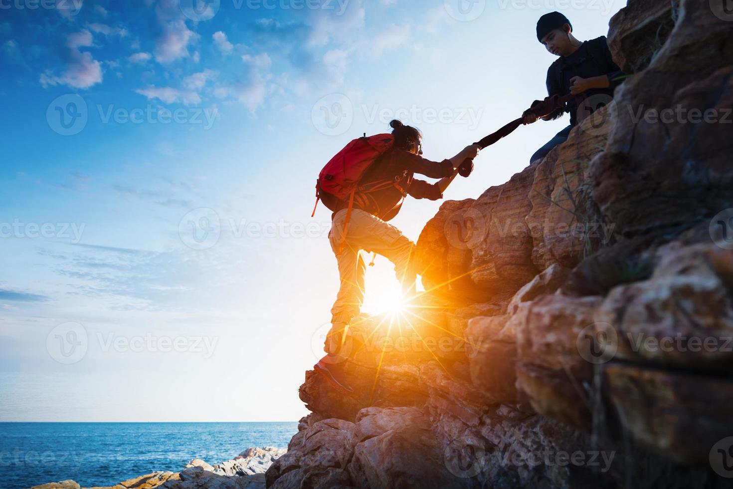 jovem casal asiático subindo na montanha, caminhadas e conceito de trabalho em equipe. foto