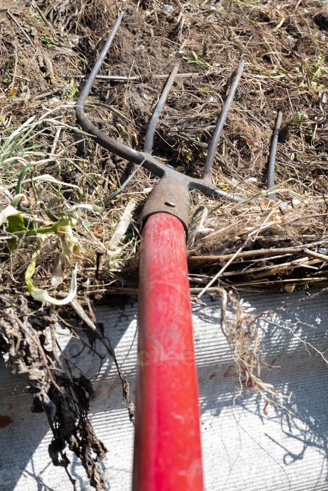 garfo com cabo vermelho para compostagem, reciclagem de resíduos de grama e jardim. garfos presos no composto. fazendo e misturando composto no quintal. fertilizante orgânico para plantas de jardim. foto