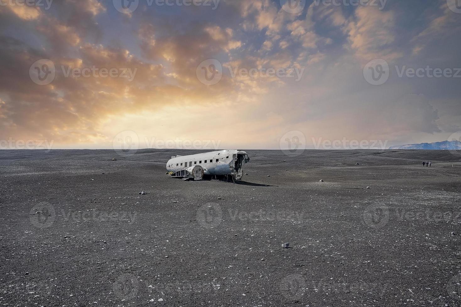 vista do naufrágio do avião danificado na praia de areia preta em solheimasandur no pôr do sol foto