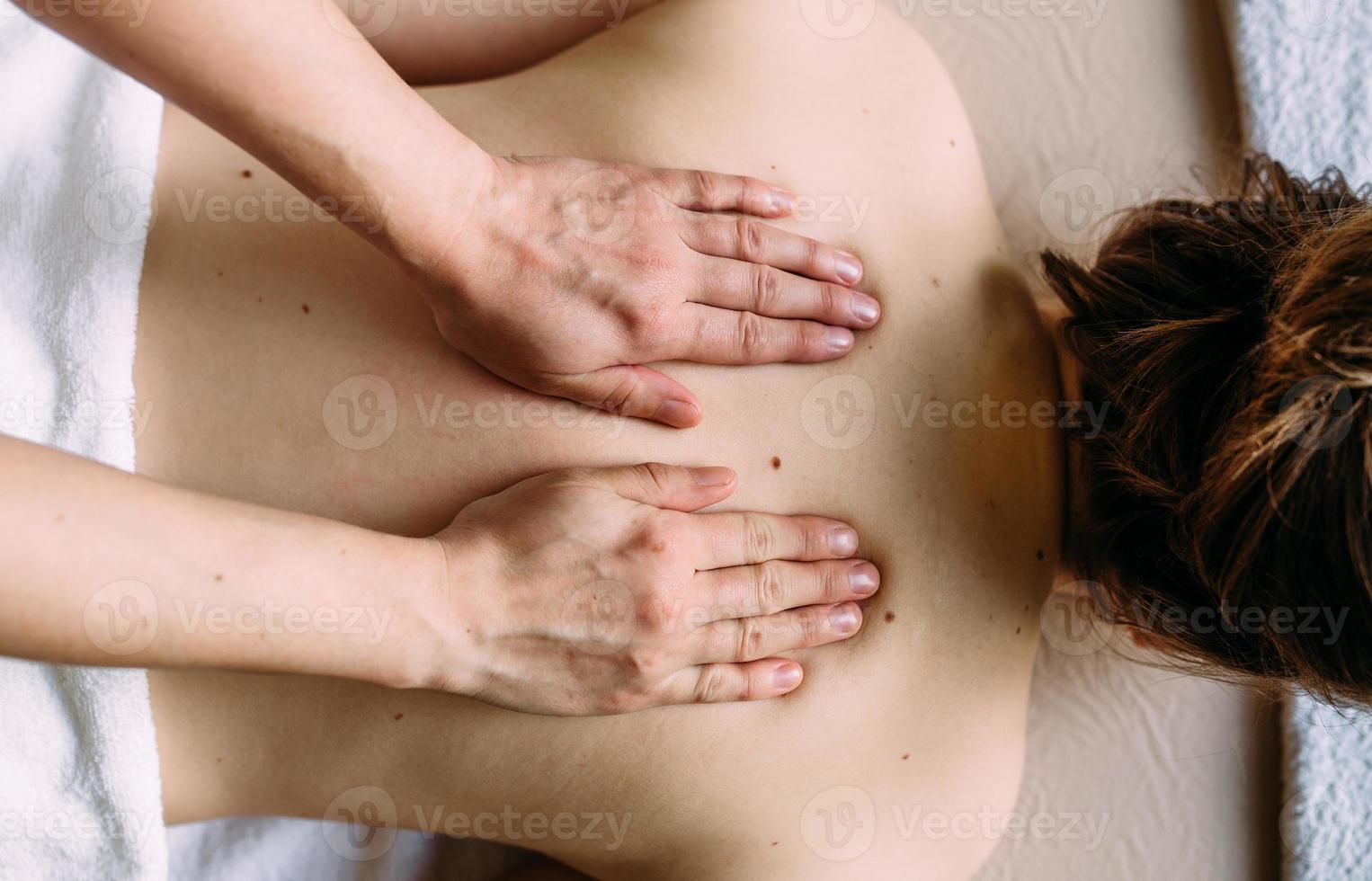 massagista fazendo massagem no corpo feminino no spa. o conceito de procedimentos cosméticos. foto