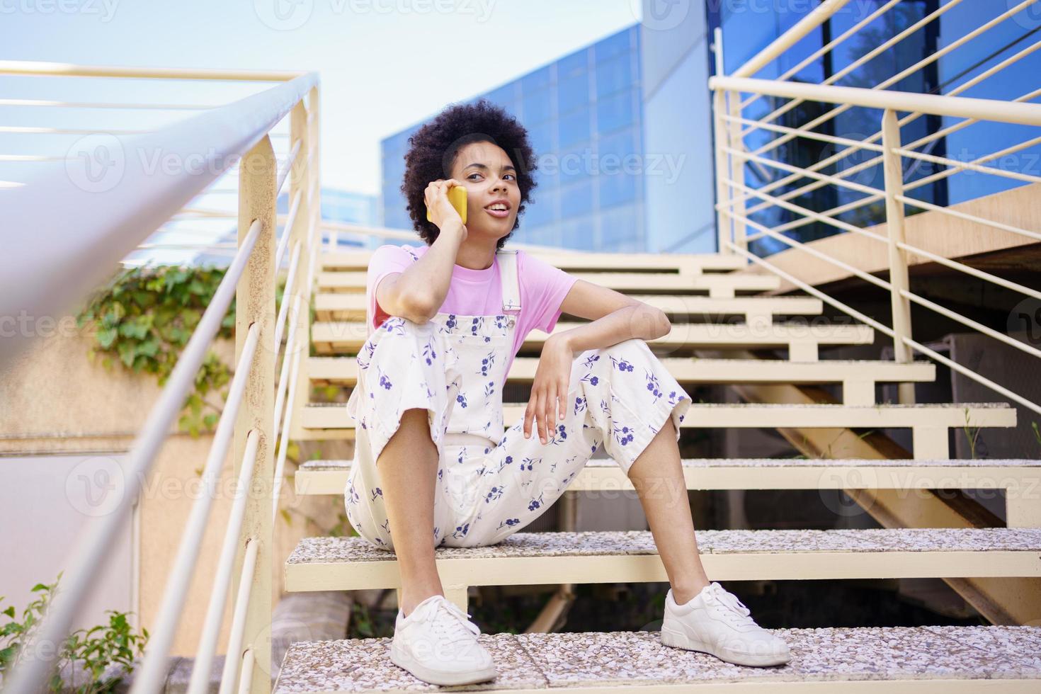 mulher negra conversando por telefone na escada foto