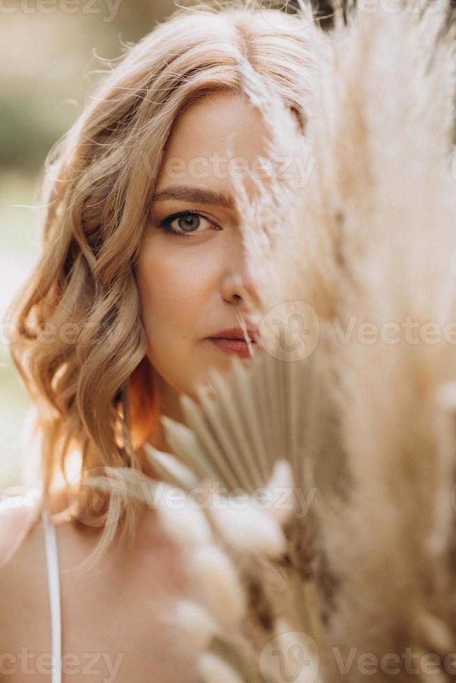 menina noiva feliz em um vestido branco claro com um buquê de flores secas foto