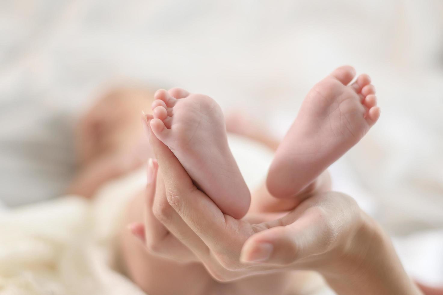 perto da mão segurando os pés do bebê recém-nascido foto