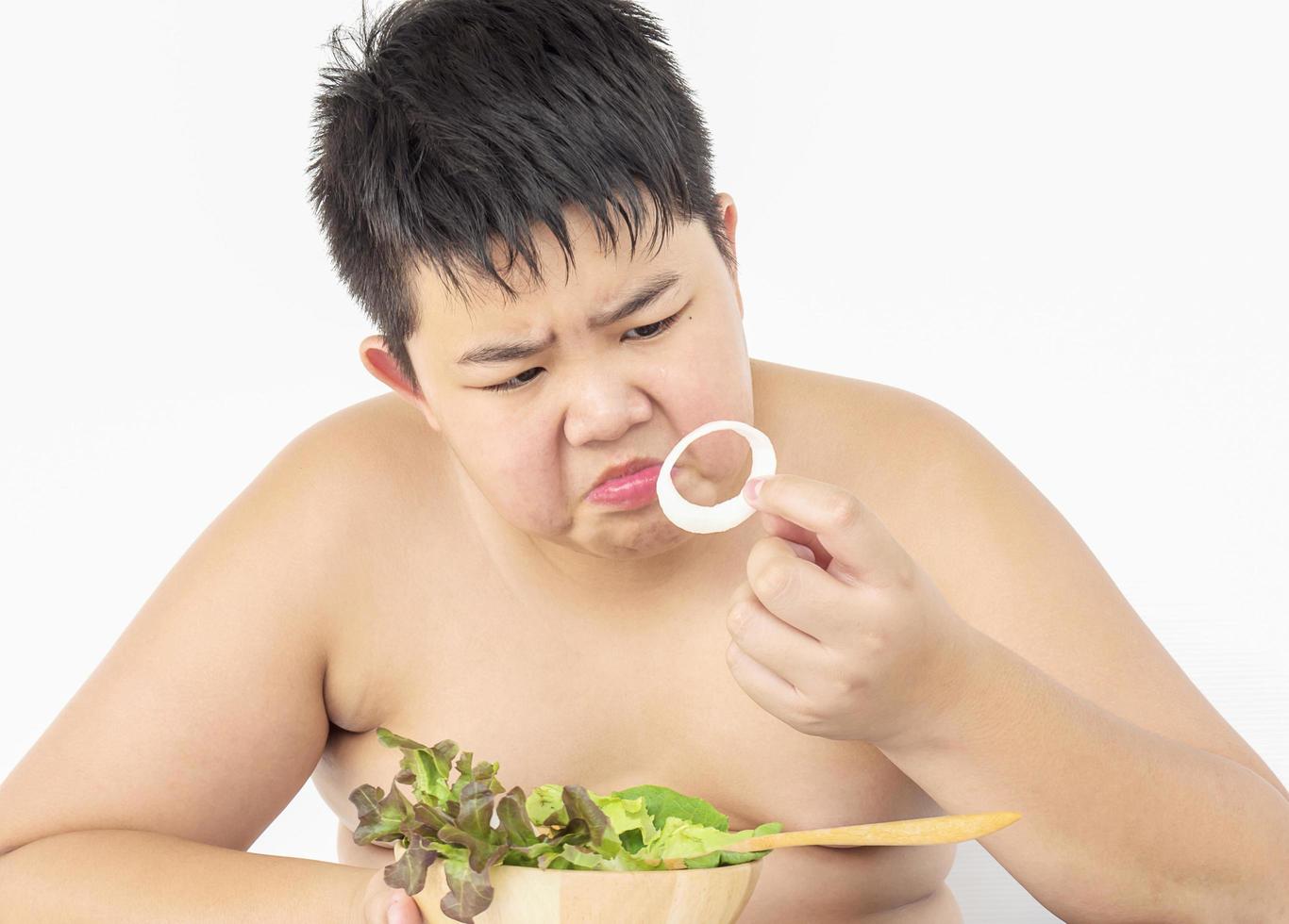 um menino gordo odeia comer salada de legumes foto