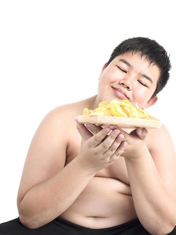 menino gordo está comendo felizmente chip isolado sobre o branco foto