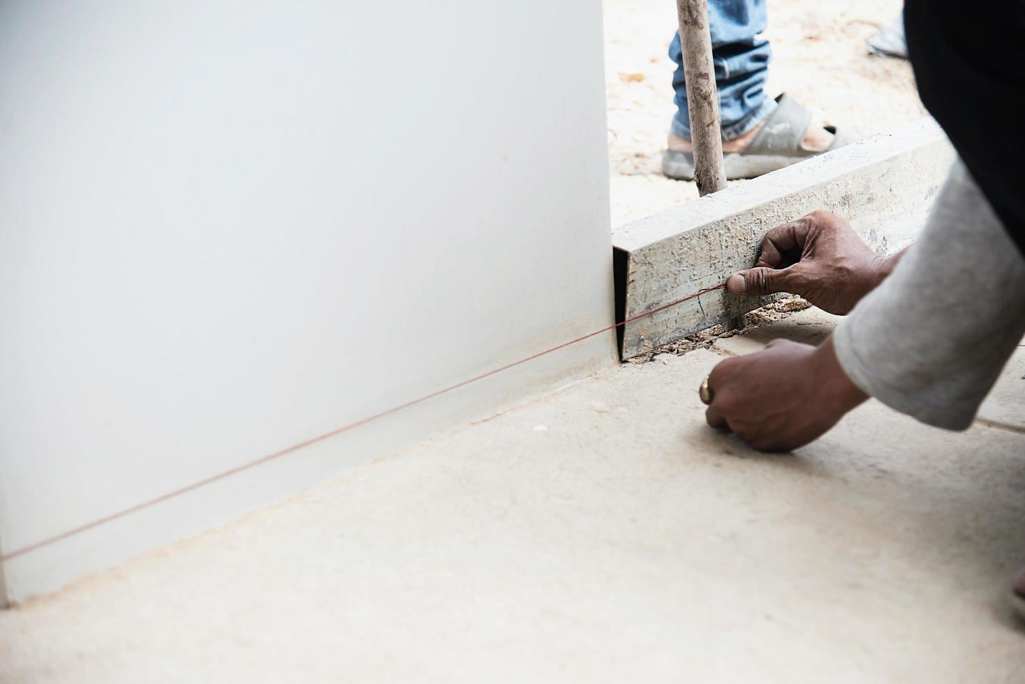 trabalhador da construção civil fazendo seu trabalho - usando linha de encaixe de substituição fina preparando-se para derramar piso de concreto foto