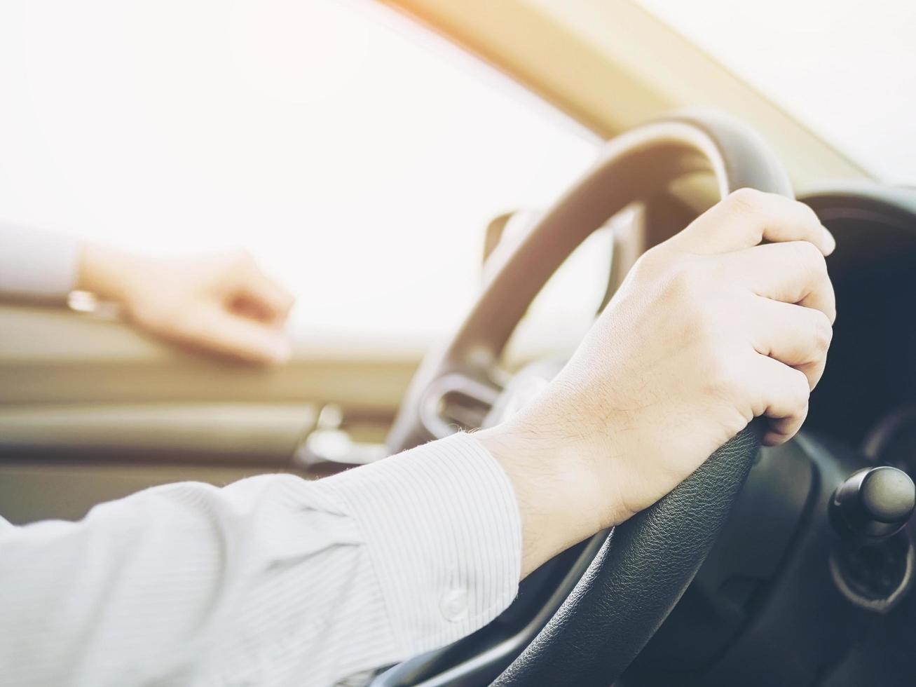 close-up de um homem dirigindo carro usando uma mão, comportamento perigoso foto
