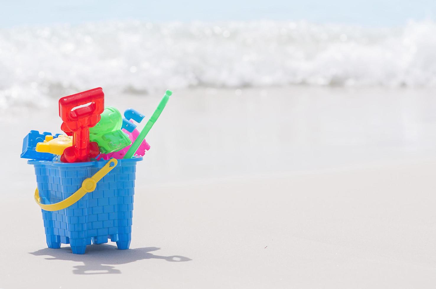balde de brinquedo na praia de areia limpa foto