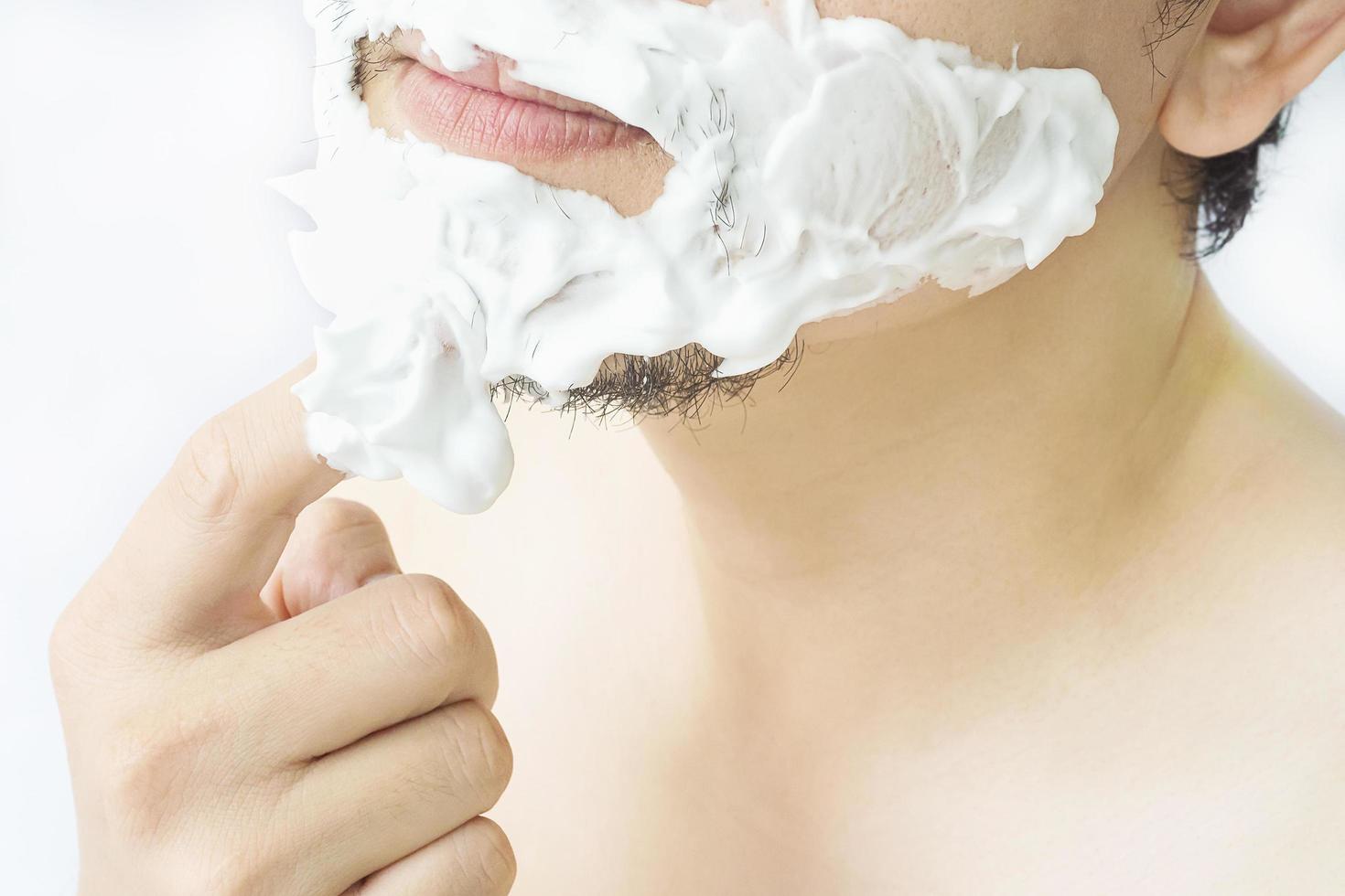 homem está espalhando espuma no rosto, prepare-se para fazer a barba foto