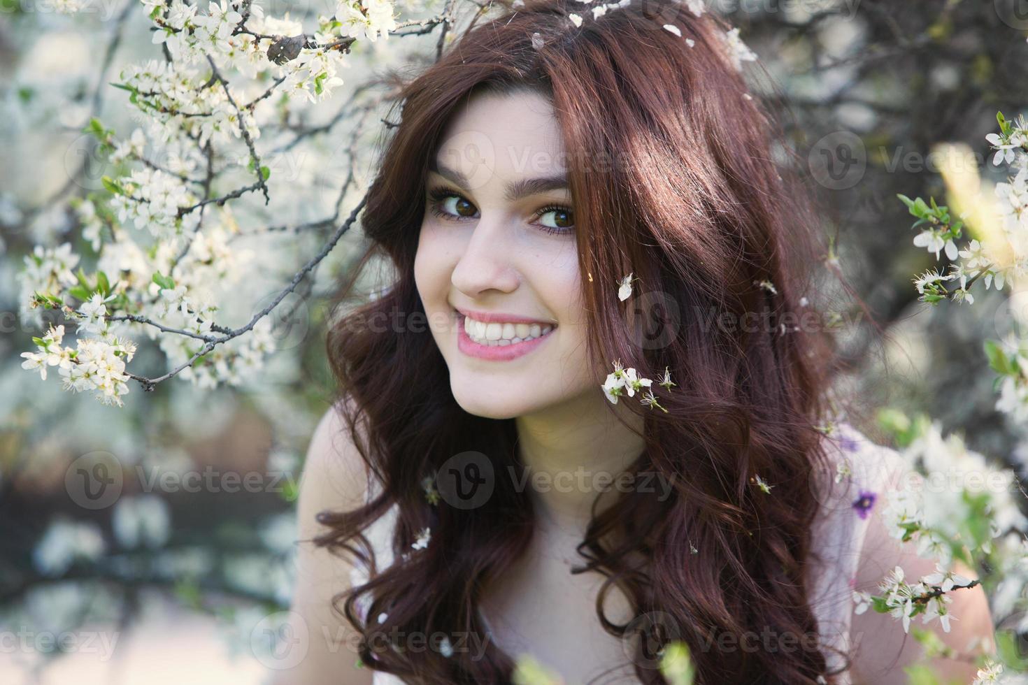 linda garota europeia branca com pele limpa no parque com árvores floridas foto