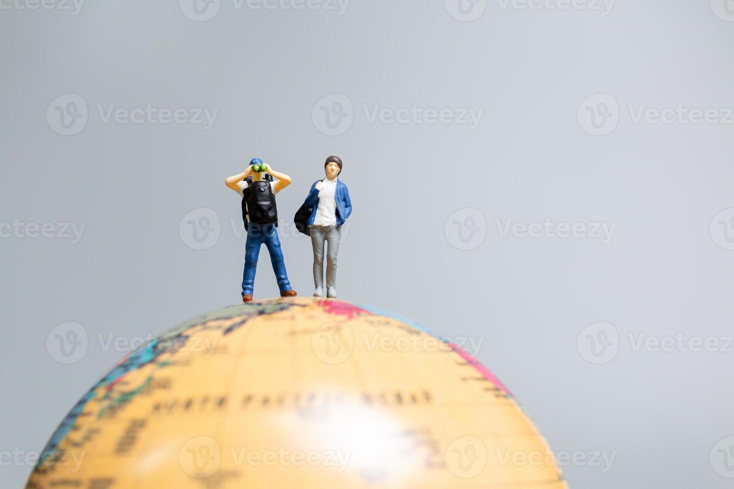 viajantes em miniatura, de pé no globo e a caminho de seu destino, foto