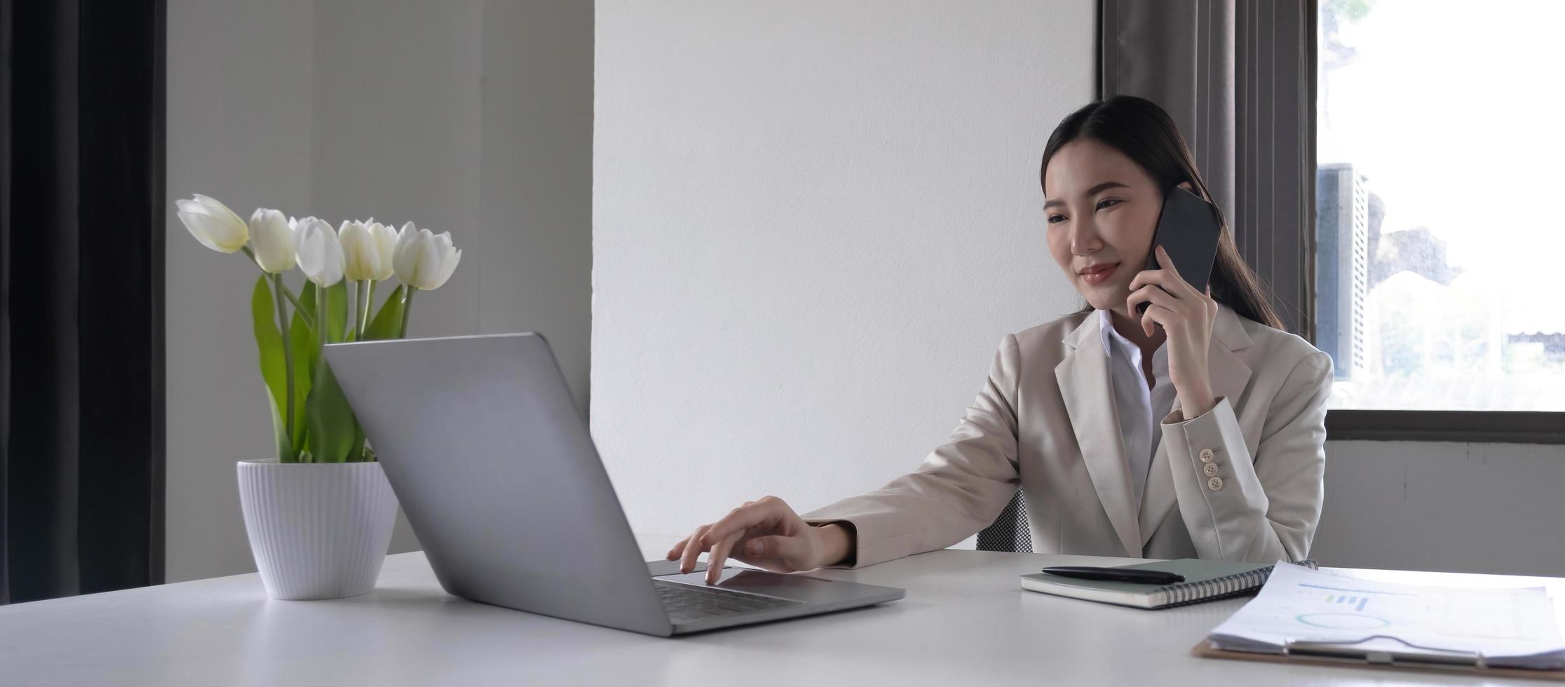 jovem empresária asiática linda encantadora sorrindo e falando no celular no escritório. foto
