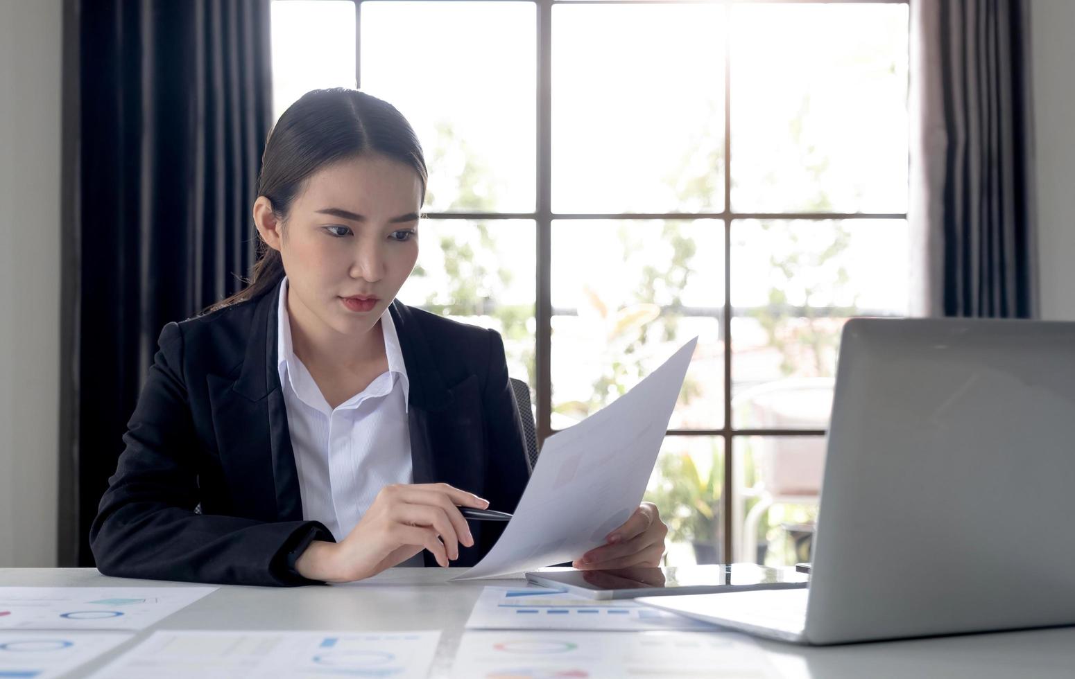 retrato de uma mulher asiática trabalhando em um computador tablet em um escritório moderno. fazer um relatório de análise de conta. conceitos de sistema financeiro e fiscal de informações de investimento imobiliário foto