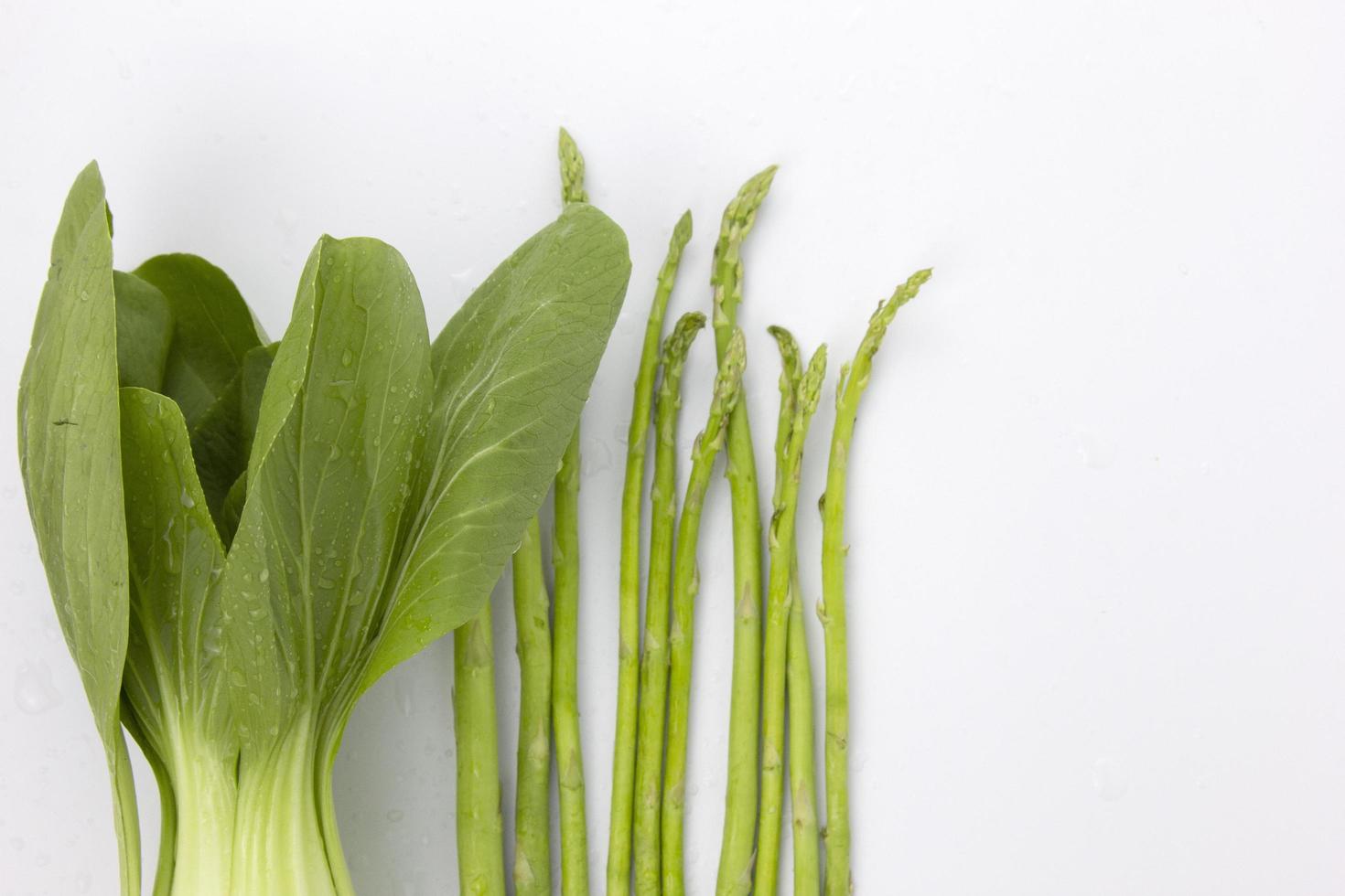 espargos verdes e vegetais orgânicos isolados no fundo branco usado para design de conceitos de culinária saudável foto