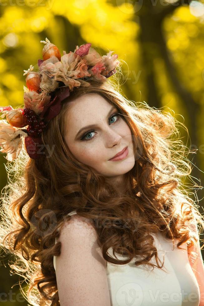 jovem segurando um monte de folhas de plátano amarelas. retrato de outono de jovem. garota ruiva na floresta de outono foto