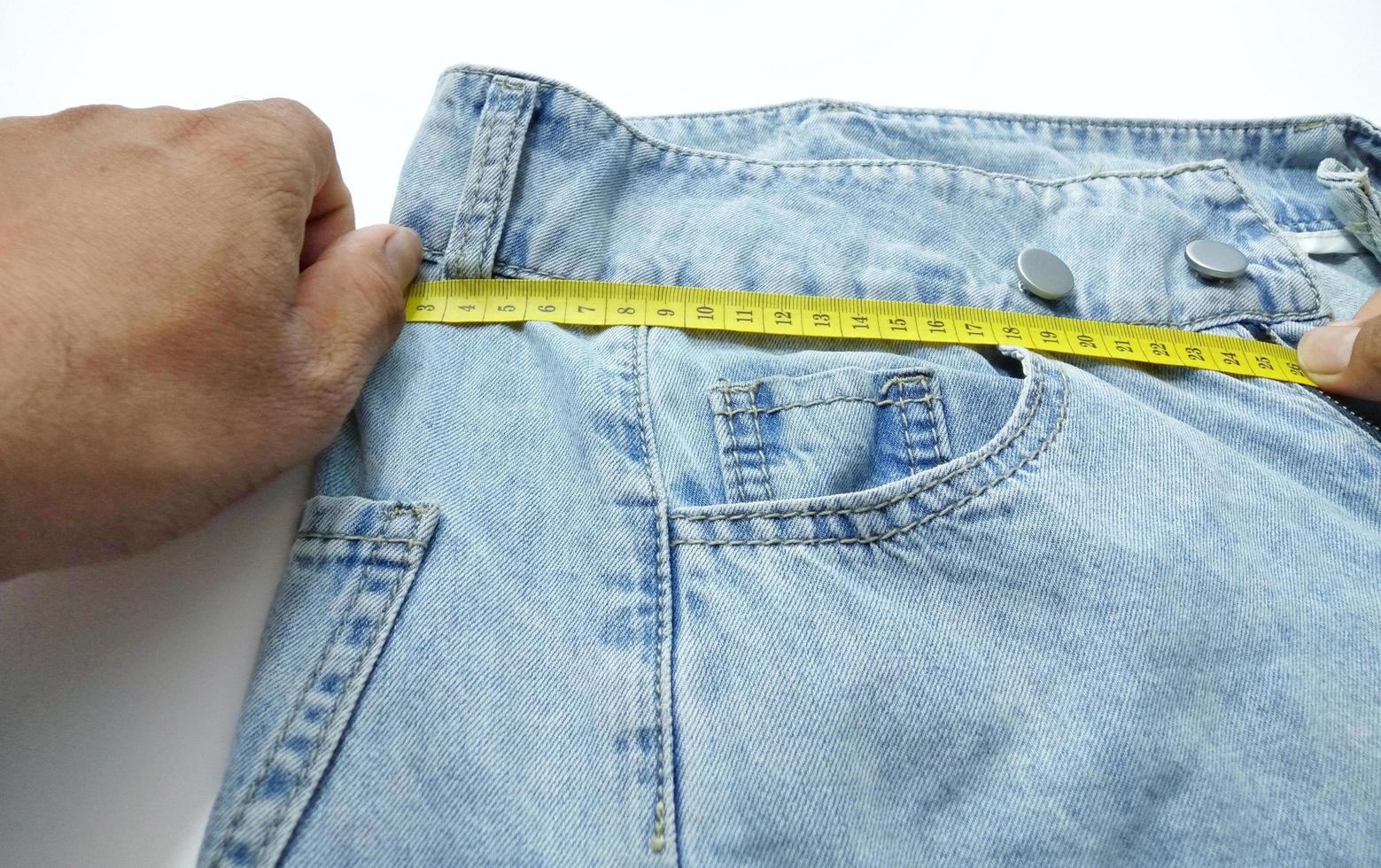 jeans de mão estão puxando a fita métrica amarela. foto
