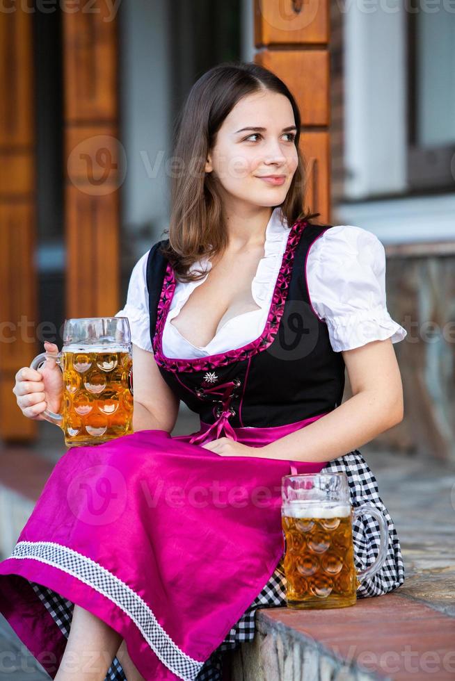 mulher russa sexy vestido bávaro segurando canecas de cerveja. foto