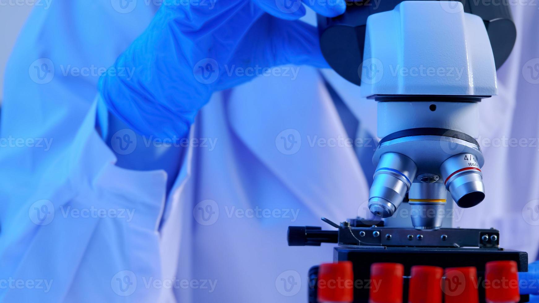 cientista asiático fazendo algumas pesquisas e olhando através de um microscópio em laboratório. foto