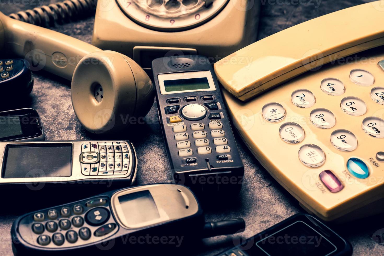 um telefone antigo com discagem rotativa, telefone fixo e celular obsoleto em um fundo grunge. foto