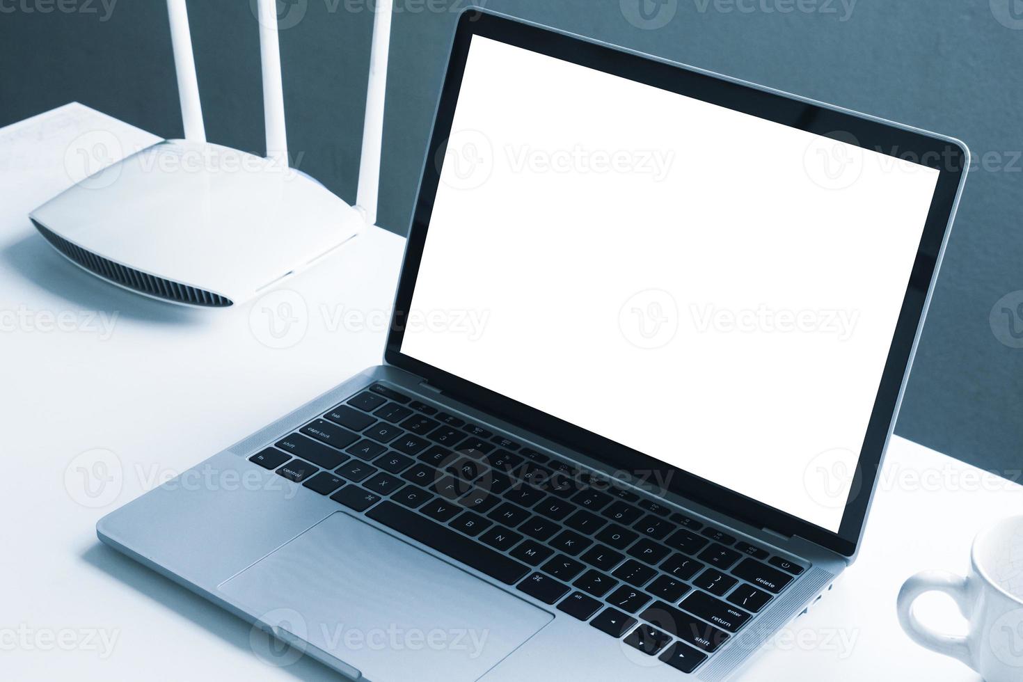 computador portátil de tela em branco e dispositivo roteador em cima da mesa foto