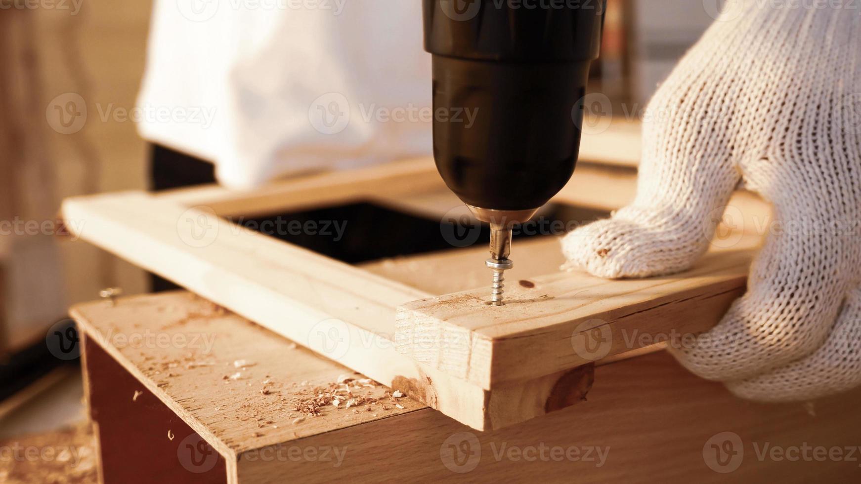 close-up de carpinteiro usando broca para aparafusar pedaços de placa no local. foto
