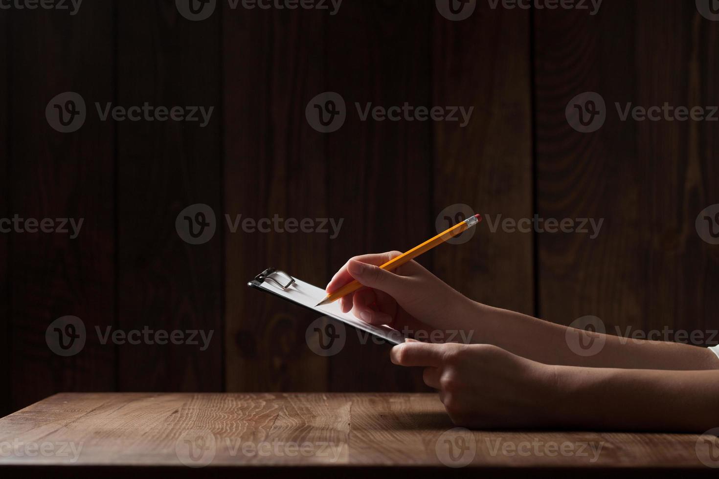 closeup da mão de uma mulher escrevendo no papel sobre a mesa de madeira foto