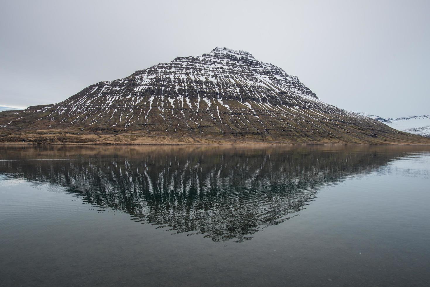o reflexo da montanha holmatindur da cidade de eskifjordur do leste da islândia. foto