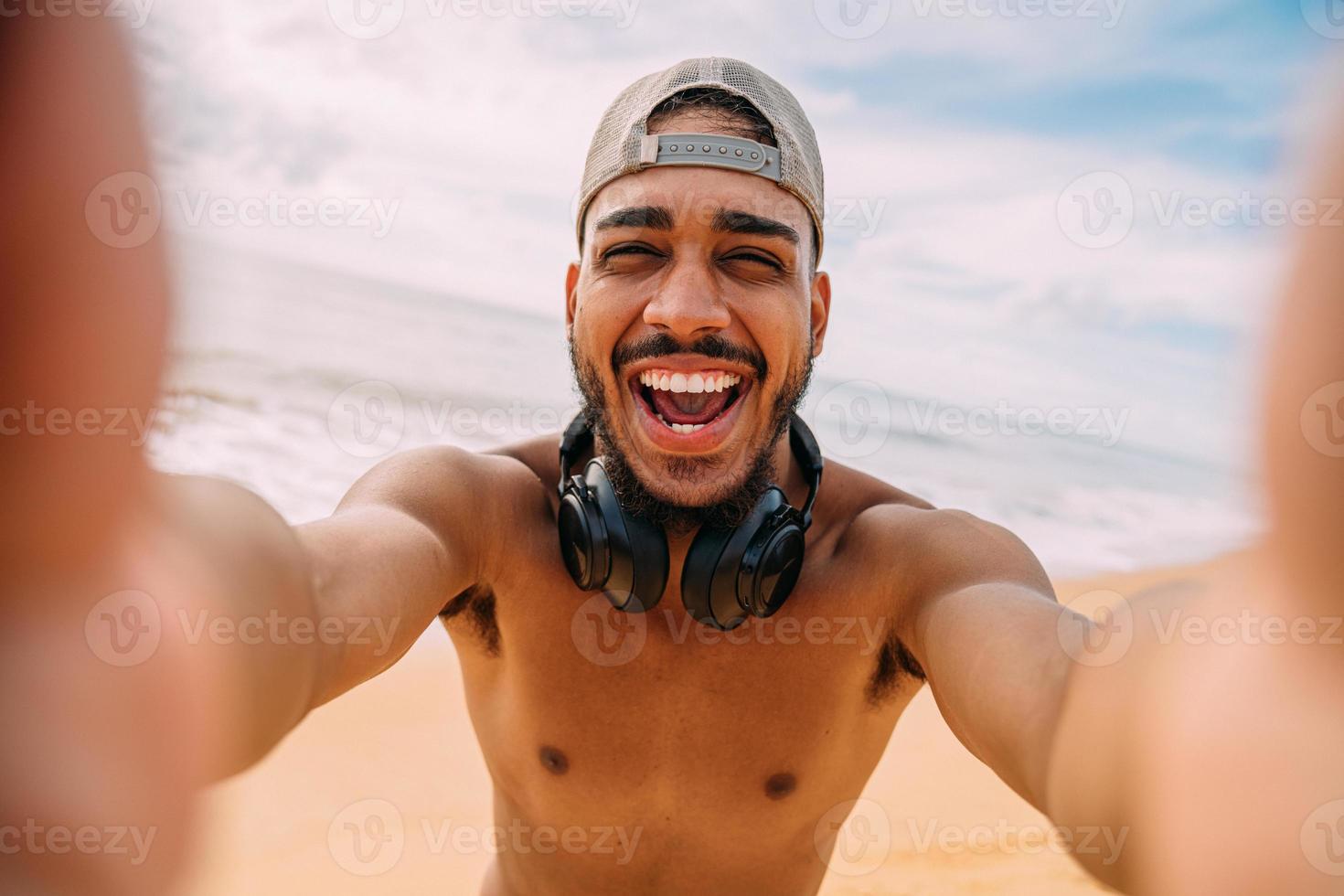 amigável sorridente américa latina jovem. homem vestindo boné e fones de ouvido, segurando e olhando para a câmera foto