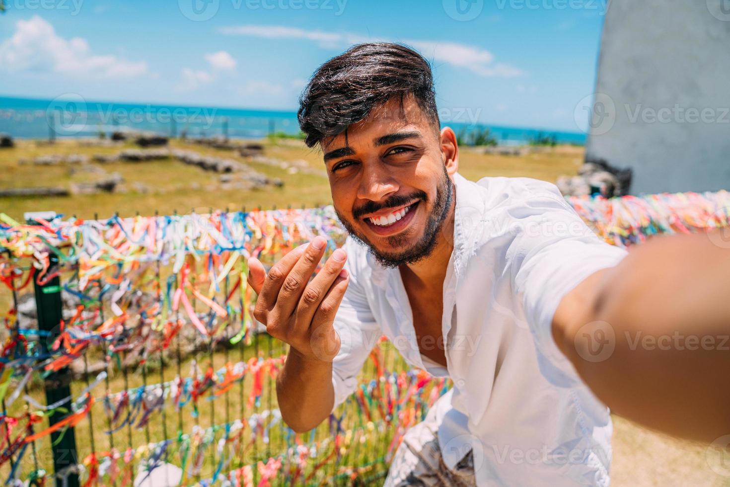 amigável jovem latino-americano convidando para vir ao brasil, confiante e sorrindo, fazendo um gesto com a mão, sendo positivo e amigável foto