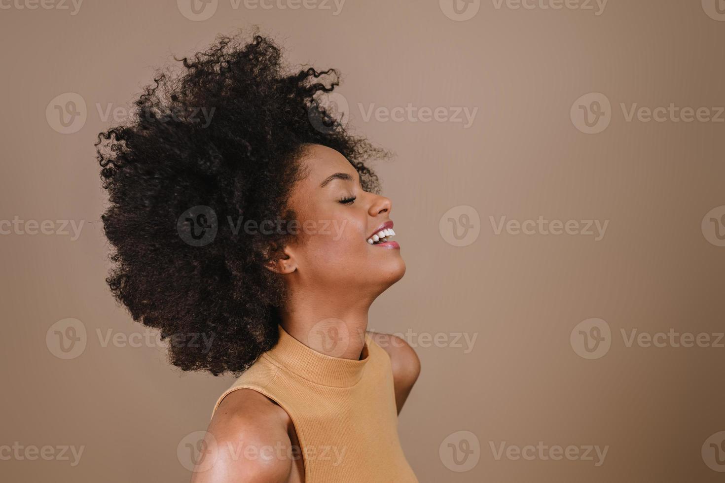 lado uma jovem afro latina sorridente. alegria, positivo e amor. lindo cabelo estilo africano. fundo de estúdio pastel. foto