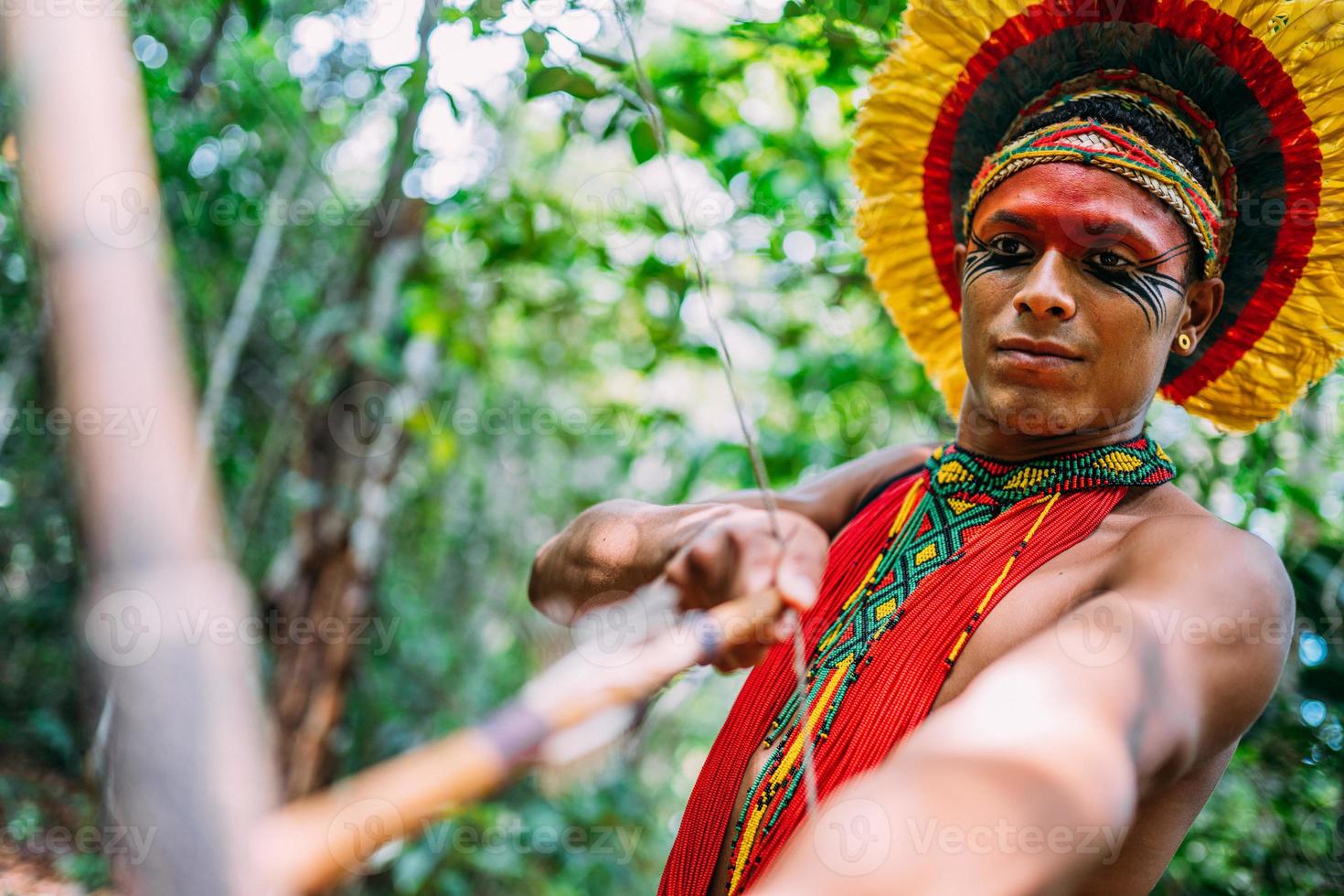 índio da tribo pataxo usando arco e flecha. índio brasileiro com cocar de penas e colar foto