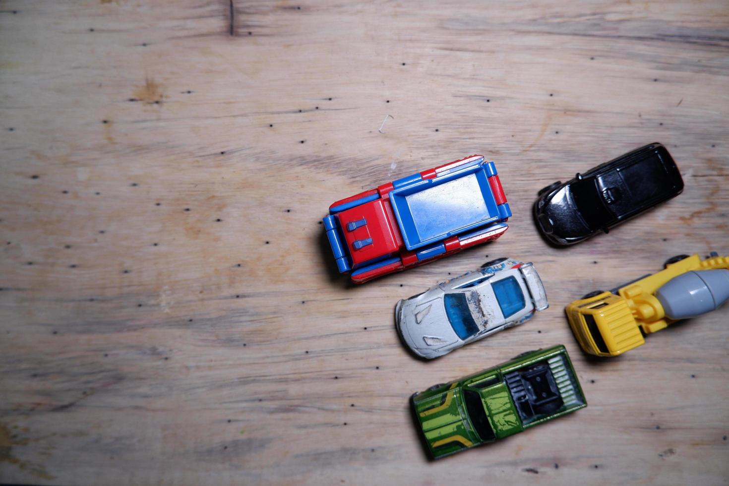 vários carrinhos de brinquedo alinhados ordenadamente na madeira. carros de brinquedo fotografados de cima. alguns carros de brinquedo no canto inferior direito. foto
