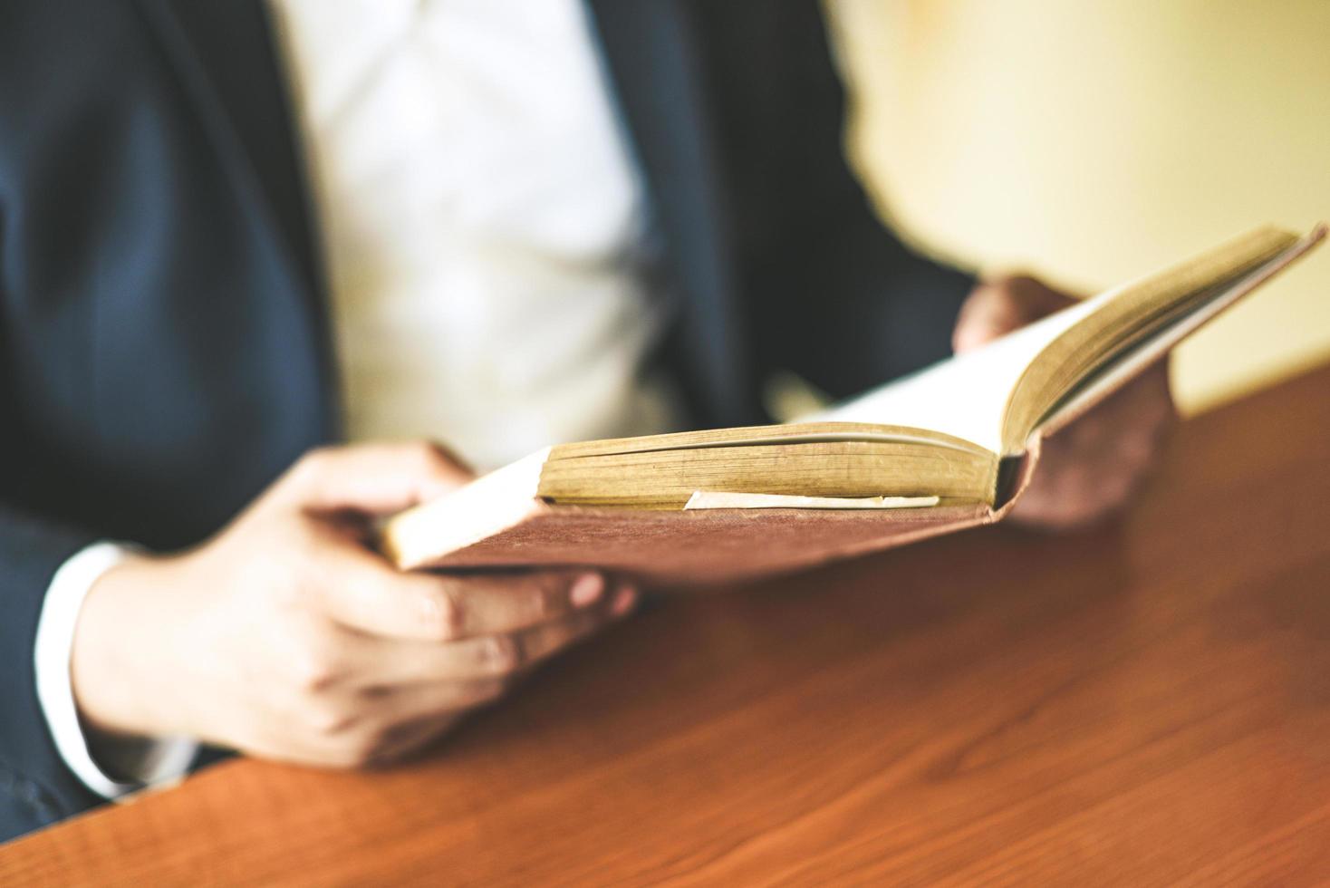 homem de negócios ou estudante segurando um livro na mão - conceito de estudo de educação empresarial homem lendo livro sobre a mesa foto