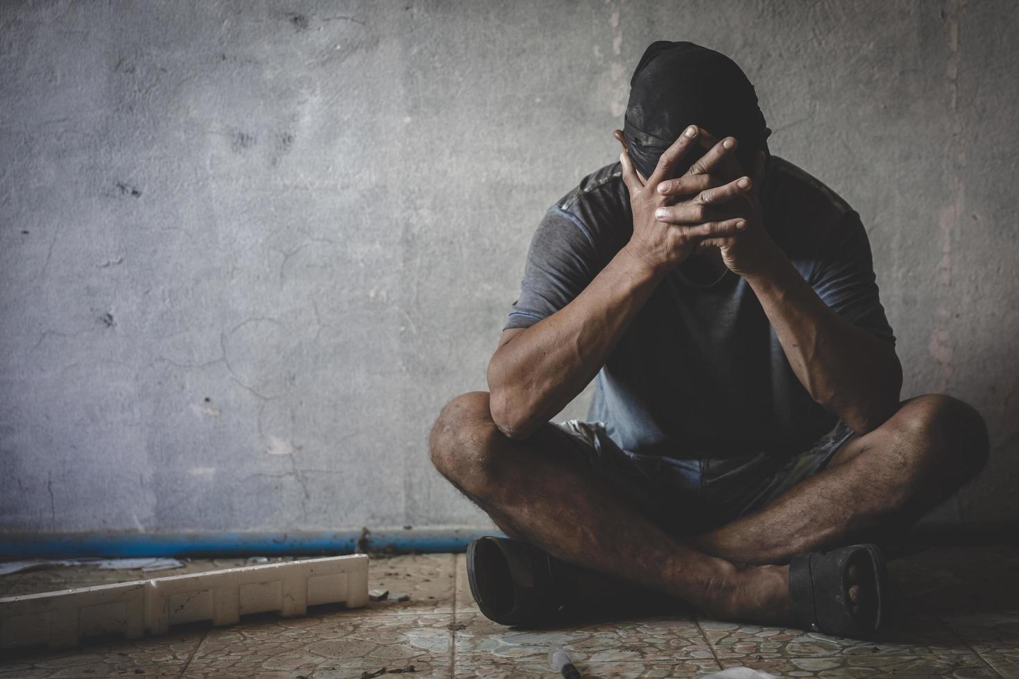 homem deprimido sentado em prédio abandonado. homem triste chorando. drama. conceito solitário e infeliz, viciado em drogas. foto