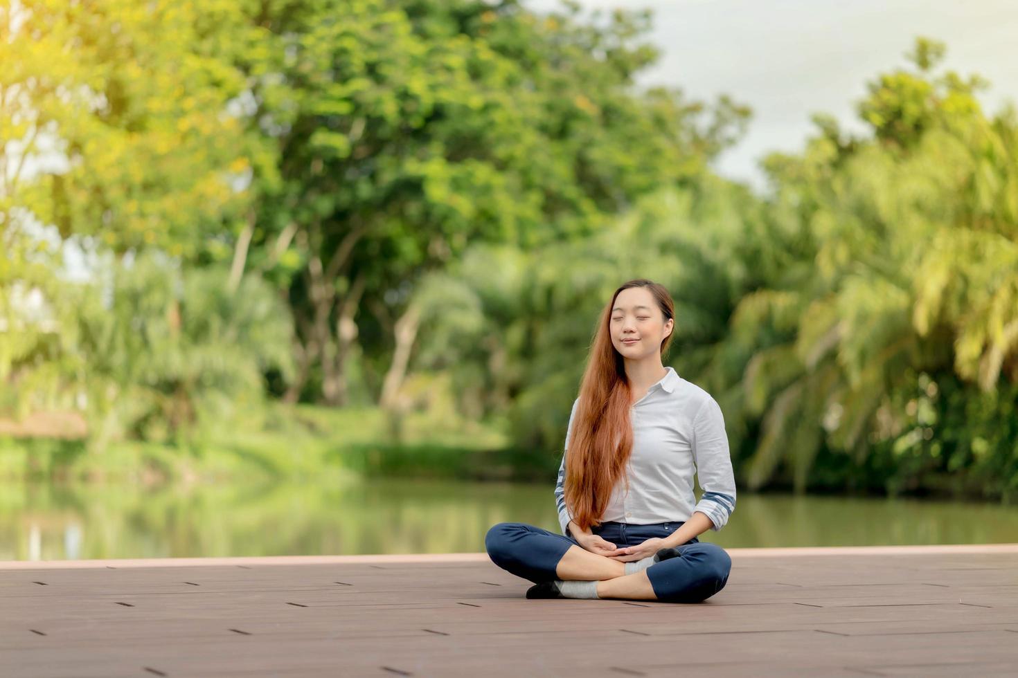 mulher asiática vestindo uma meditação de vestido branco perto do canal foto