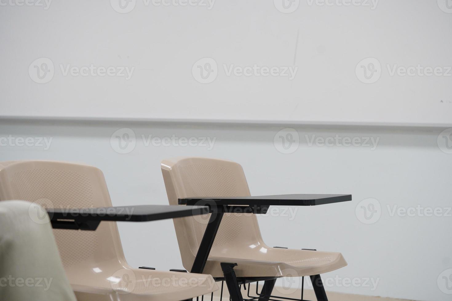 aula vazia na universidade ou escola com cadeiras e mesa lateral, as cadeiras são dispostas em filas. foto