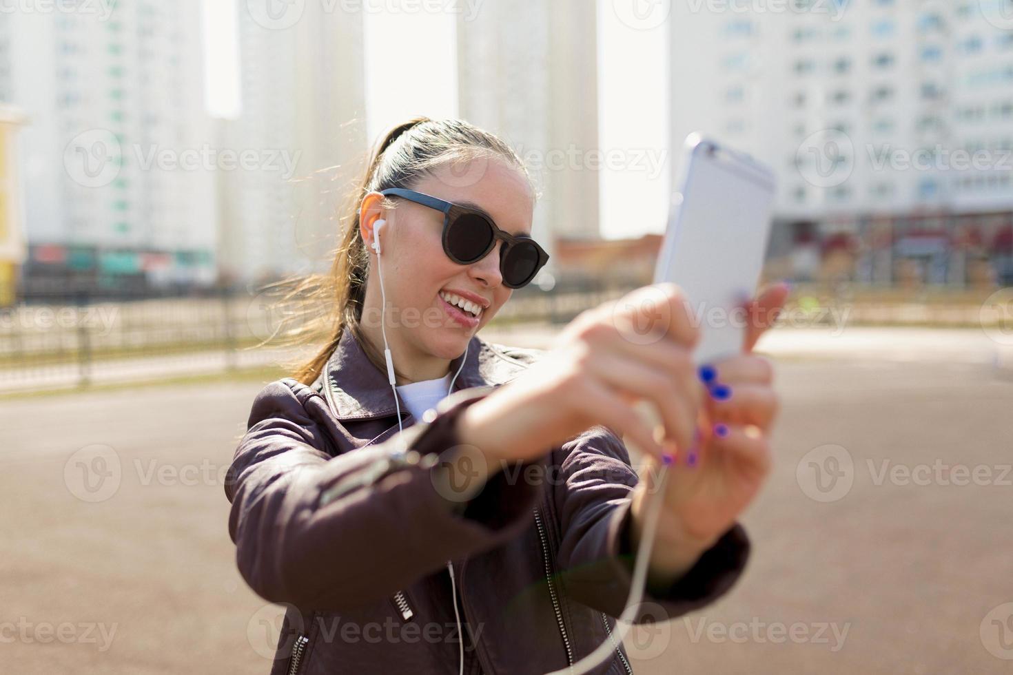 mulher sorridente atraente fazendo selfie ao ar livre foto