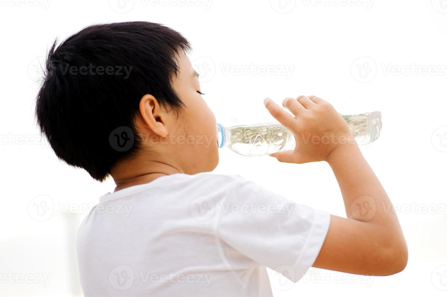 menino bebe água da garrafa foto