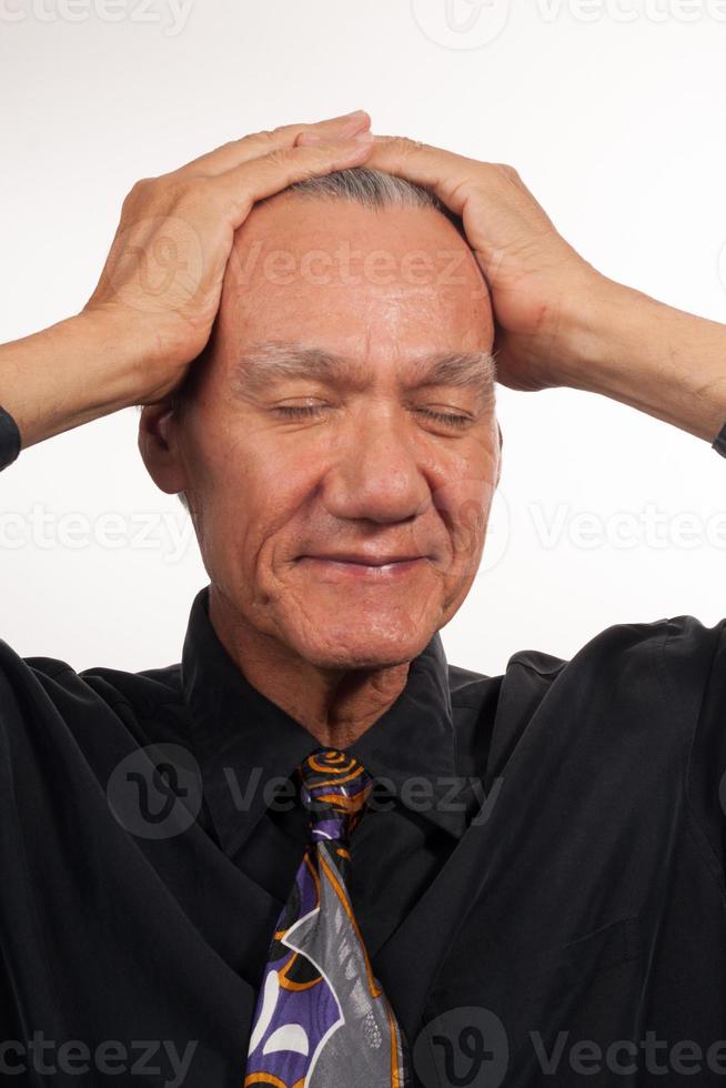 homem maduro, vestindo uma camisa preta e gravata com as mãos na cabeça foto