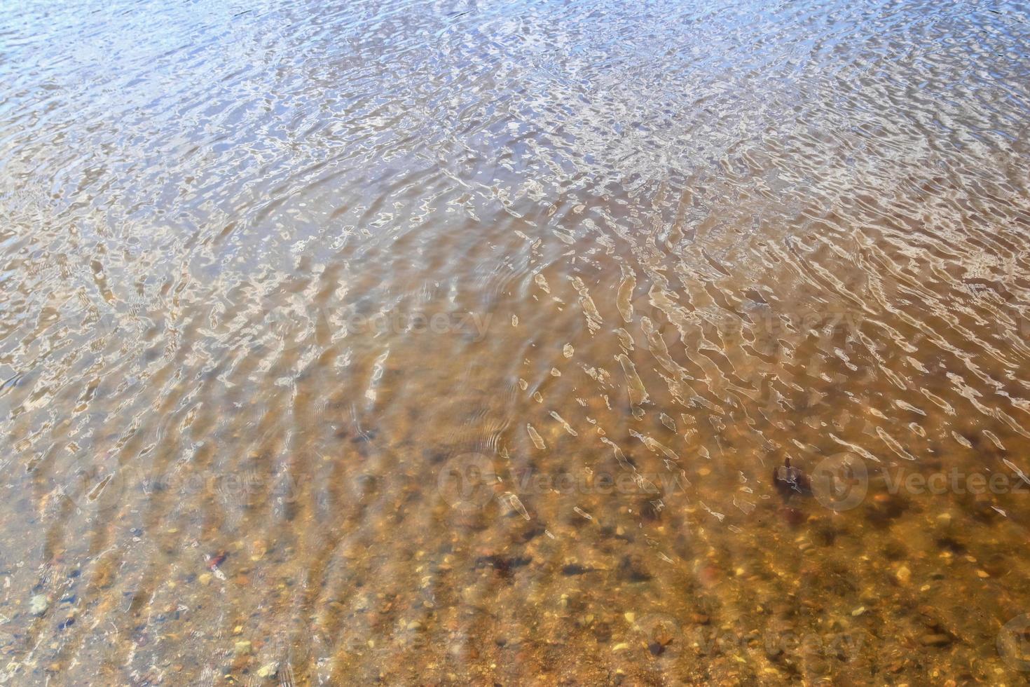 vista detalhada de perto em superfícies de água com ondulações e ondas e a luz do sol refletindo na superfície foto