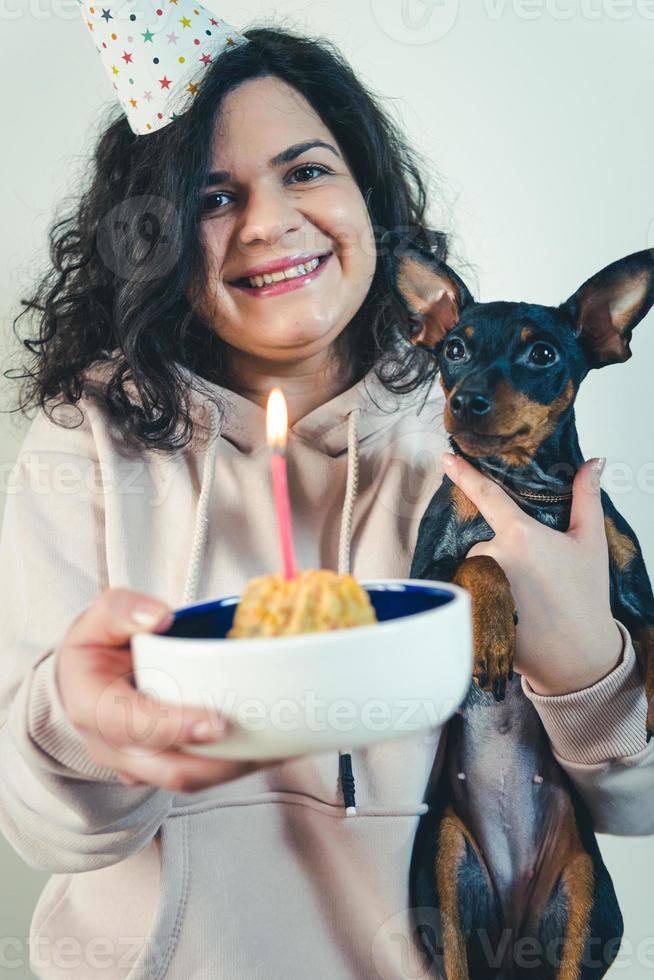 jovem feliz dando bolo caseiro para seu cachorro, dentro de casa foto