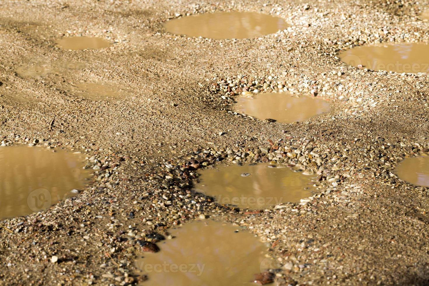 um grande número de buracos e poços na estrada de areia foto