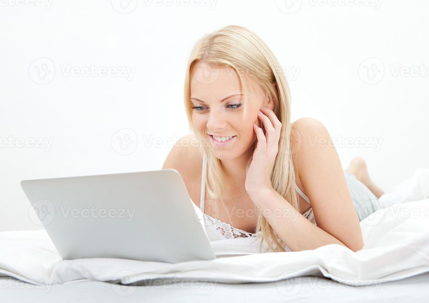 jovem mulher bonita usando o laptop na cama foto