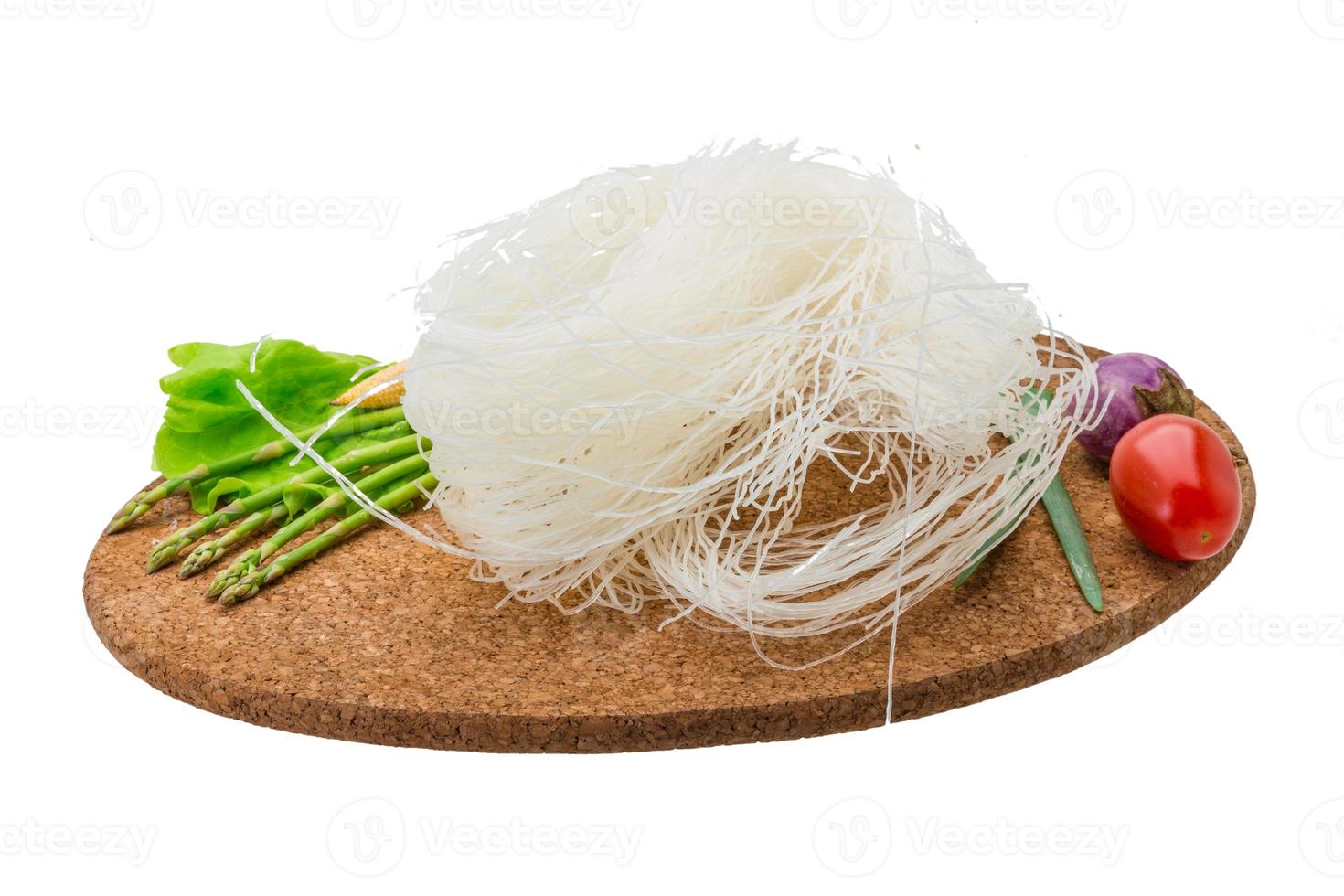 macarrão de arroz cru na placa de madeira e fundo branco foto