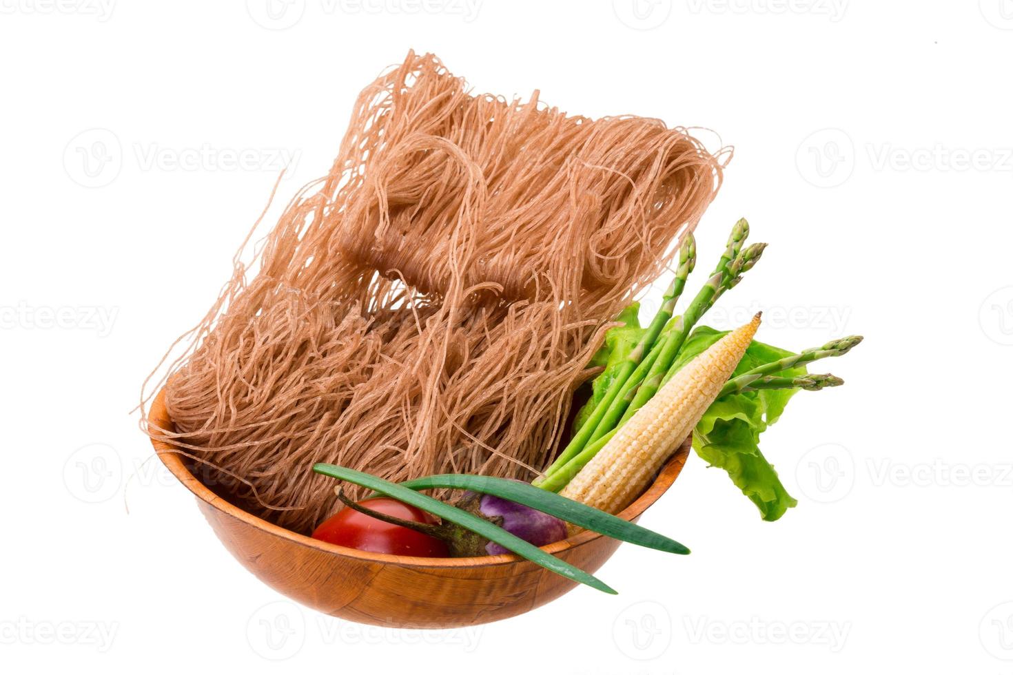 macarrão de arroz cru em uma tigela no fundo branco foto