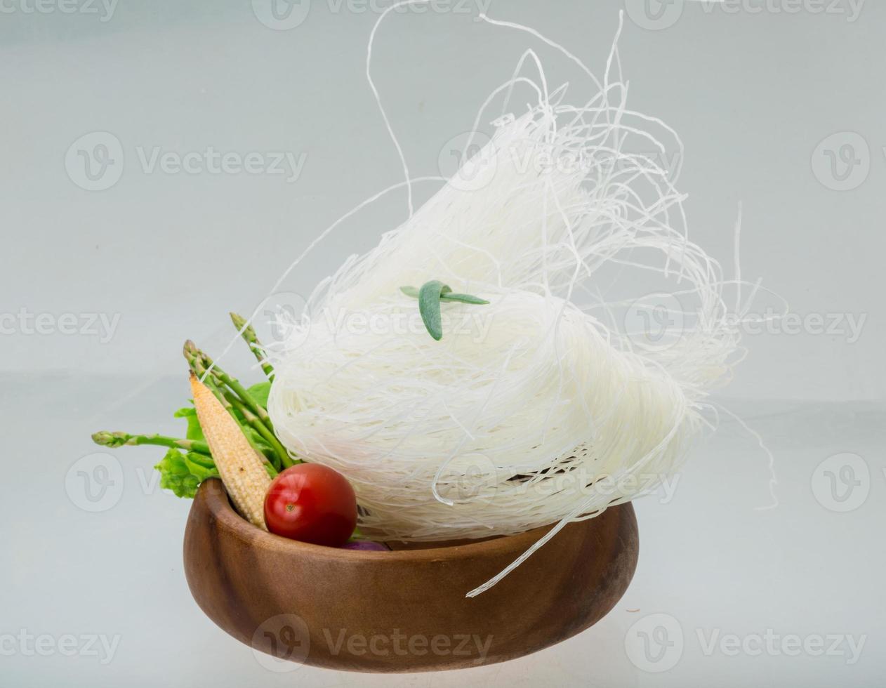 macarrão de arroz cru em uma tigela no fundo branco foto