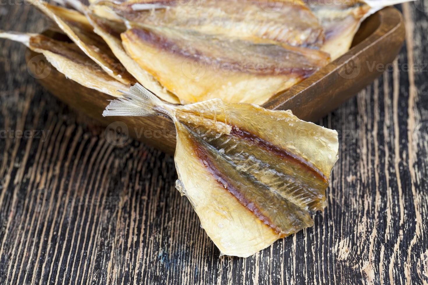 peixe pequeno seco e massacrado em uma mesa de madeira foto