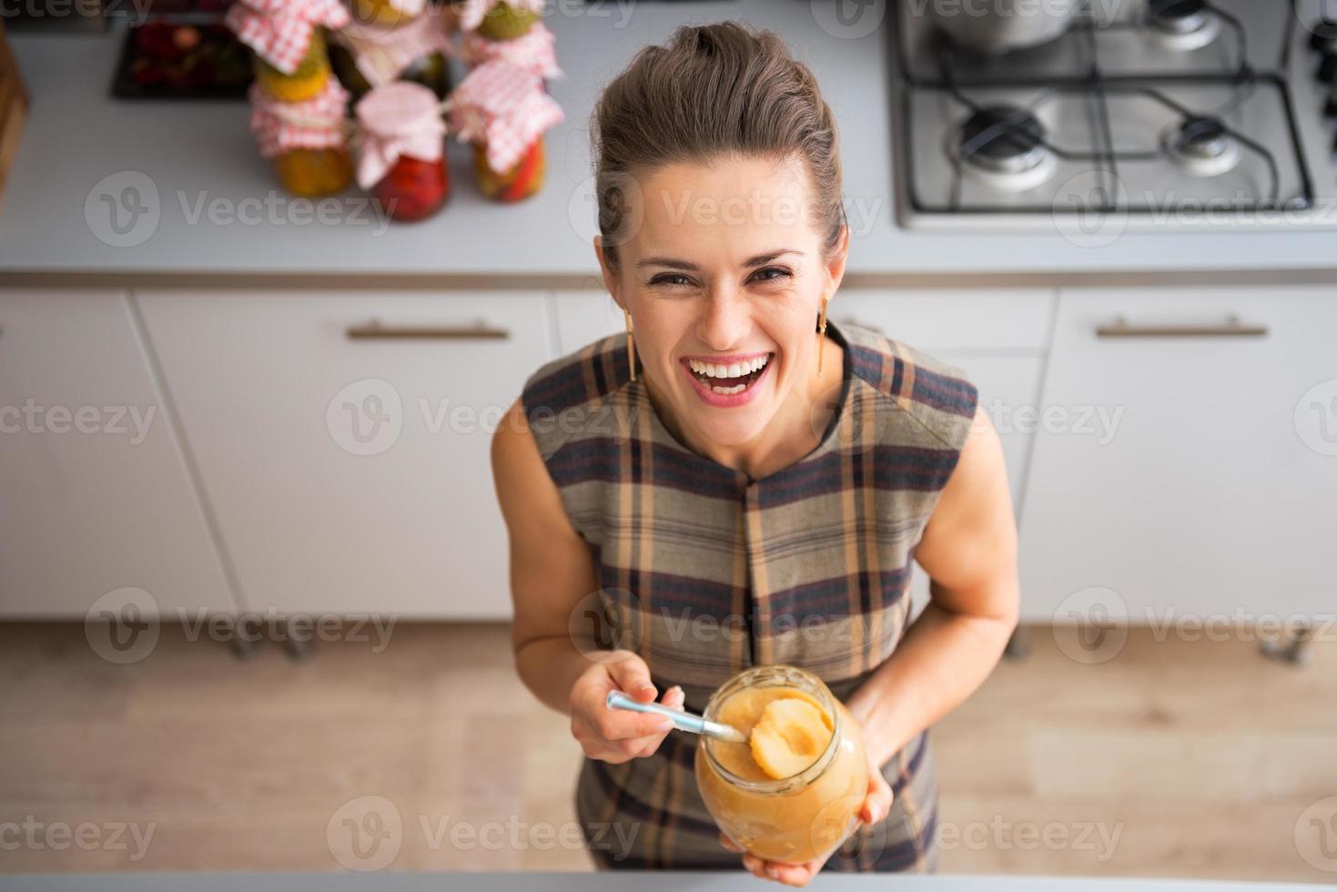 retrato de dona de casa jovem feliz, segurando o frasco com geléia de maçã foto