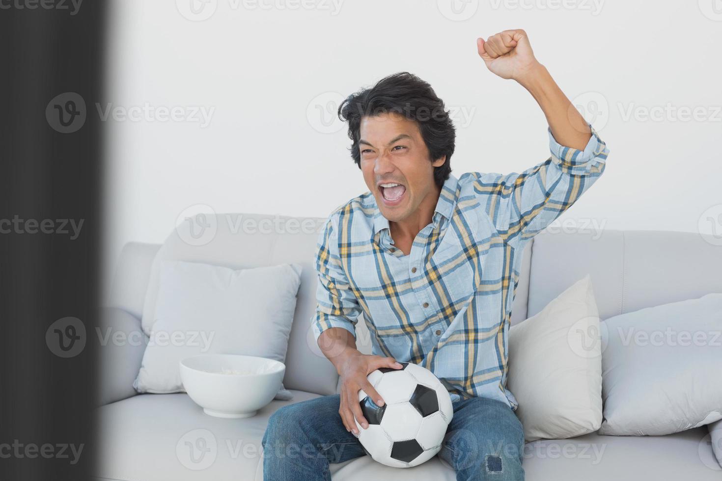 fã de futebol torcendo enquanto assiste tv foto